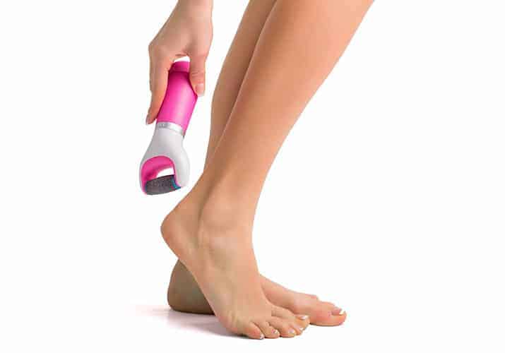 Lady using electric callus remover on heels of feet