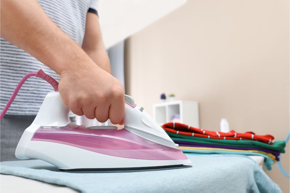 Man ironing clothes on board at home